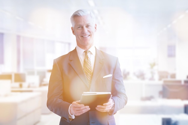 Portrait d'homme d'affaires senior devant son bureau moderne avec tablette