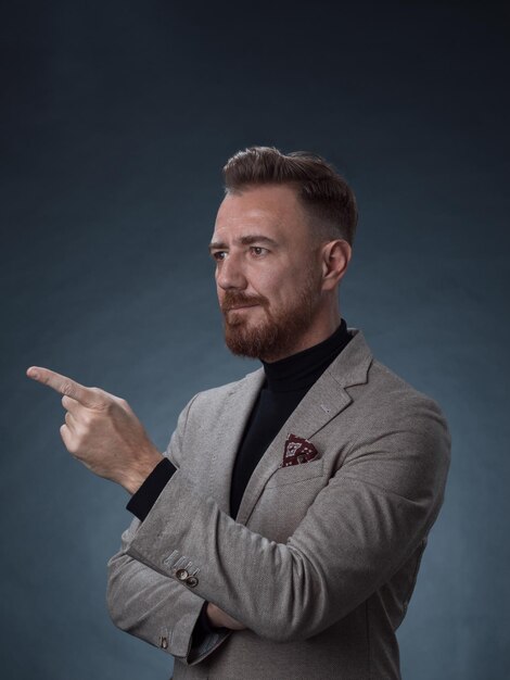 Portrait d'un homme d'affaires senior élégant et élégant avec une barbe et des vêtements d'affaires décontractés en studio photo isolé sur fond sombre gesticulant avec les mains. Photo de haute qualité