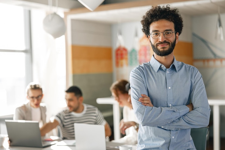 Photo portrait d'un homme d'affaires souriant dans un bureau moderne sur le fond de ses collègues