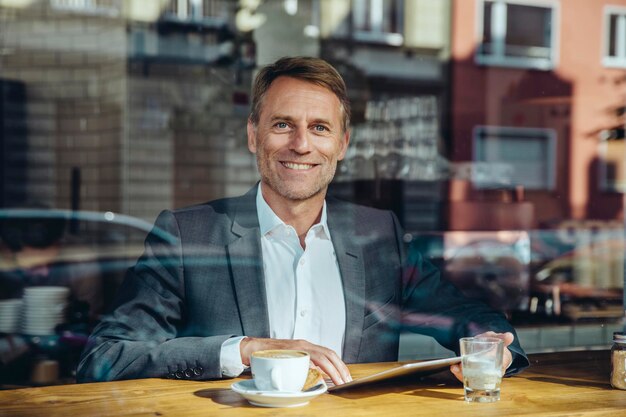 Portrait d'homme d'affaires souriant avec tablette au café