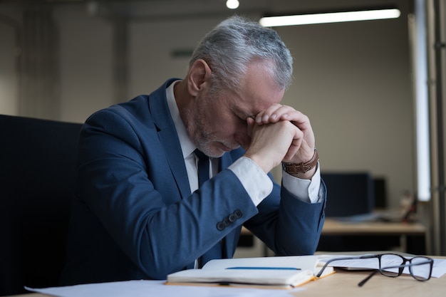 Portrait d'homme d'affaires stressé fatigué assis au bureau