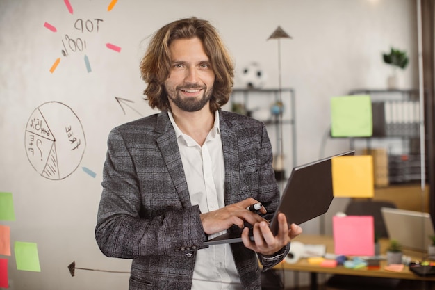 Portrait d'homme d'affaires tenant un ordinateur portable dans la salle de bureau