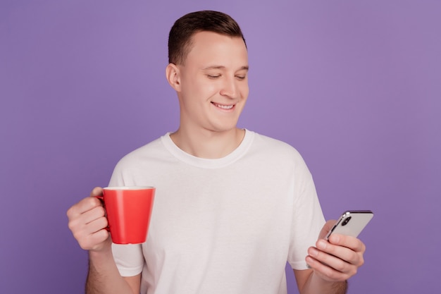 Portrait d'homme d'affaires tenir une tasse de café à l'écran du téléphone sur fond violet