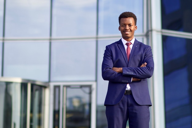 Portrait d'un homme africain noir sérieux et confiant, jeune homme d'affaires afro-américain en costume formel avec cravate debout à l'extérieur du bureau d'affaires avec ses mains croisées