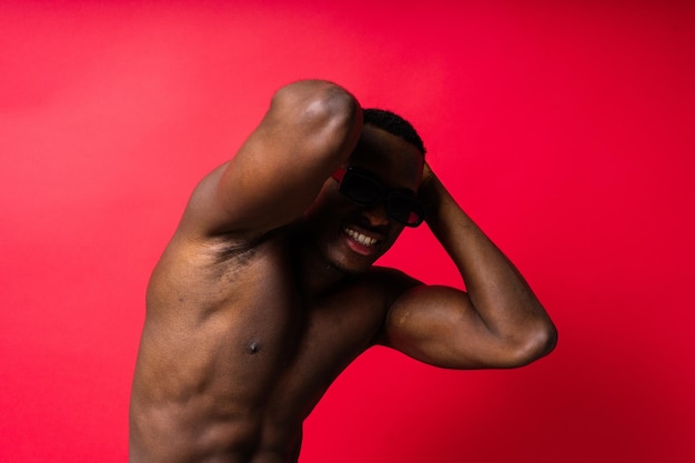 Portrait d'un homme afro-américain athlétique en topless souriant au fond jaune rouge et noir