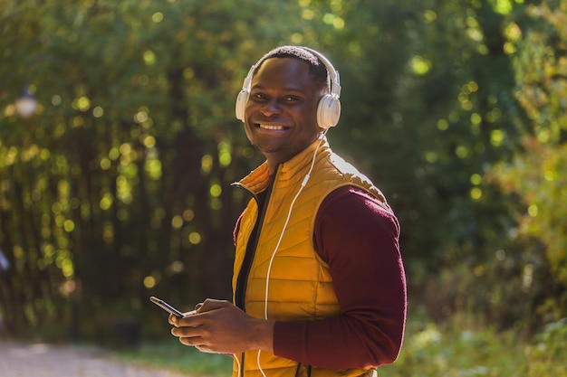 Portrait Un homme afro-américain écoute de la musique dans l'espace de copie du parc d'automne et place pour le texte Application Gadget et concept de service de streaming