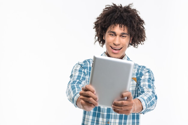 Portrait d'un homme afro-américain gai à l'aide d'un ordinateur tablette isolé sur un mur blanc