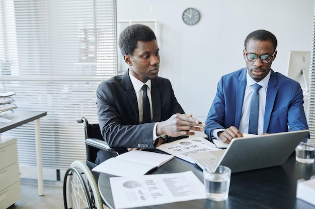 Portrait d'un homme afro-américain handicapé lors d'une réunion d'affaires avec un partenaire discutant des finances