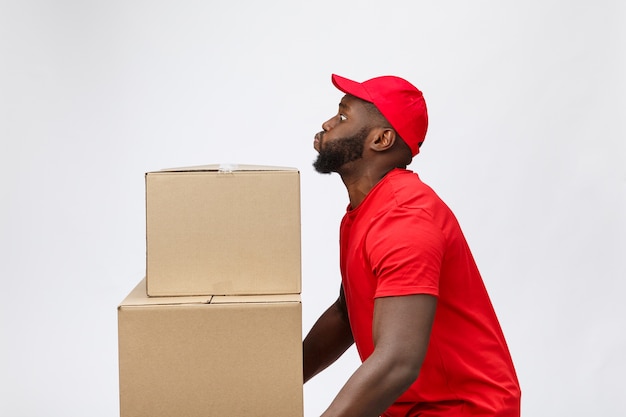 Portrait d'homme afro-américain de livraison en chemise rouge. il soulève des caisses lourdes