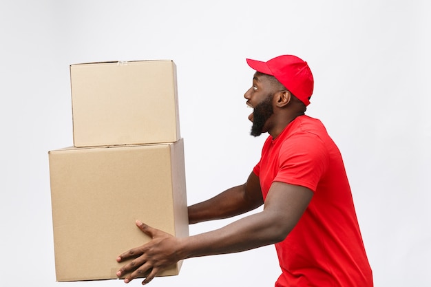 Portrait d'homme afro-américain de livraison en chemise rouge. il soulève des caisses lourdes