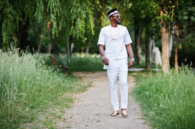 Portrait d'un homme afro-américain noir élégant et riche sur des lunettes de soleil et un chapeau de vêtements blancs