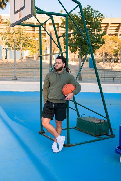 Portrait d'un homme afro-américain posant avec un ballon sur un terrain de basket