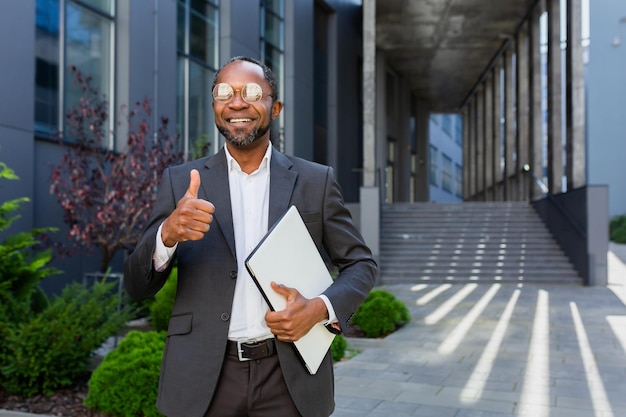 Portrait d'un homme afro-américain réussi à l'extérieur d'un immeuble de bureaux homme en costume et lunettes debout