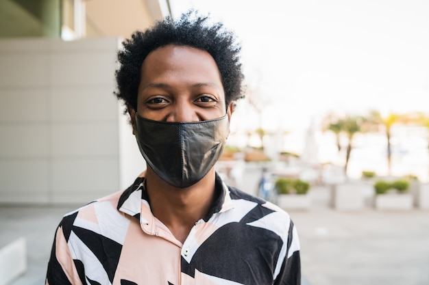 Portrait d'un homme afro-touriste portant un masque de protection tout en se tenant à l'extérieur dans la rue. Concept urbain et lifestyle.