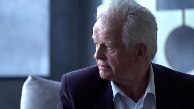 Portrait d'un homme âgé assis sur un canapé et regardant au loin