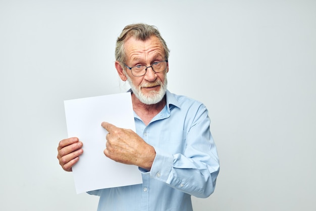 Portrait d'un homme âgé dans une chemise bleue et des lunettes une feuille de papier blanche non modifiée