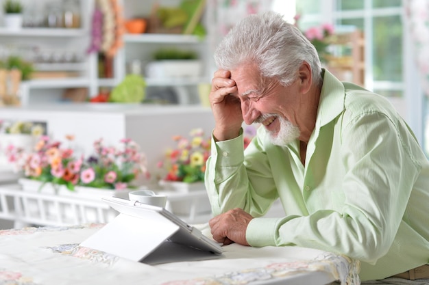 Portrait d'un homme âgé heureux à l'aide d'une tablette numérique