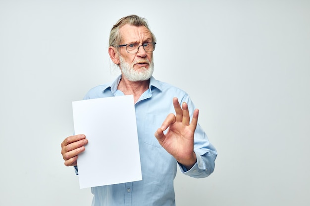Portrait d'un homme âgé heureux dans une chemise bleue et des lunettes une feuille de papier blanche vue recadrée