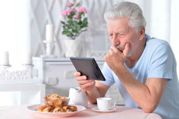 Portrait d'un homme âgé lisant un article sur une tablette