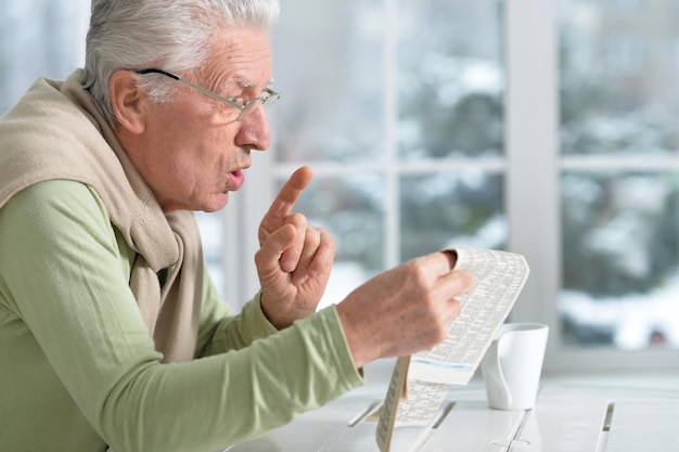 Portrait d'un homme âgé lisant le journal à la maison