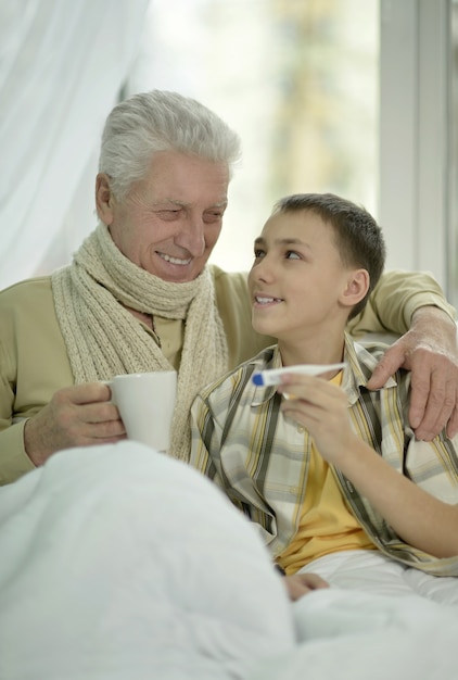 Portrait d'un homme âgé malade avec son petit-fils au lit avec