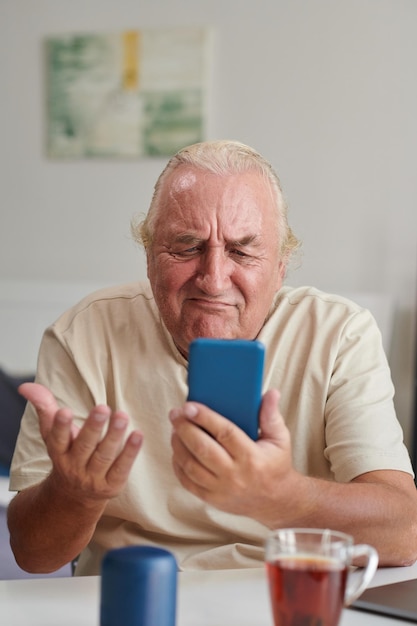 Portrait d'un homme âgé malheureux vidéo appelant son ami pour discuter de problèmes