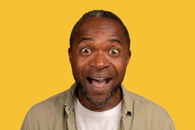 Photo portrait d'un homme d'âge moyen afro-américain surpris heureux avec la bouche ouverte regardant la caméra