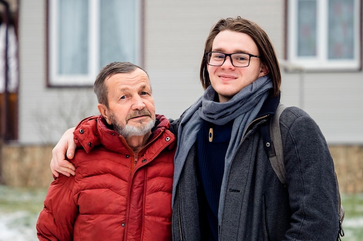 Photo portrait d'un homme âgé portant des vêtements chauds debout avec son petit-fils à l'extérieur.