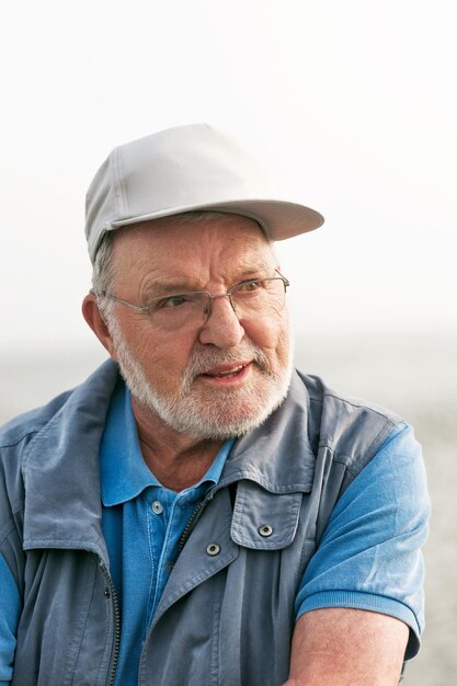 Portrait d'un homme âgé souriant et heureux à l'extérieur, regardant loin