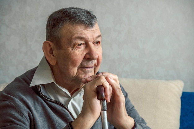 Photo portrait d'un homme âgé triste sur fond gris regard réfléchi d'un vieil aîné assis seul à la maison close-up d'un visage ridé espace de copie