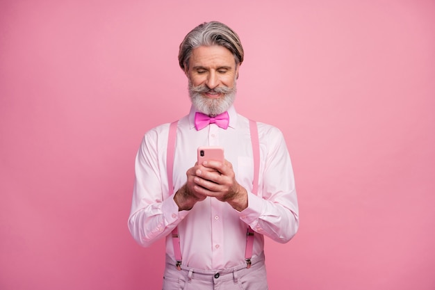 Portrait d'homme à l'aide d'un écran de téléphone numérique sur mur rose