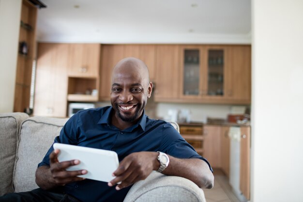 Portrait d'homme à l'aide de tablette numérique dans le salon