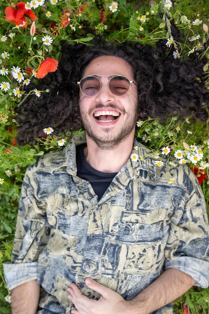 Portrait d'un homme allongé sur l'herbe dans un champ de coquelicots et marguerites