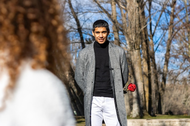 Portrait d'un homme amoureux d'une rose pour sa petite amie Jeune homme amoureux cachant une rose pour sa petite amie à l'extérieur