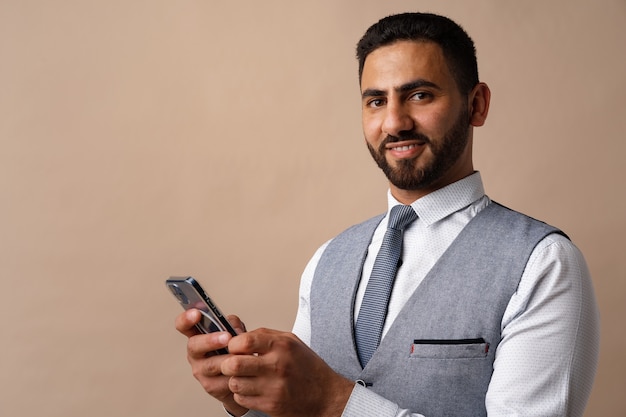 Portrait d'homme arabe à l'aide de son smartphone en studio