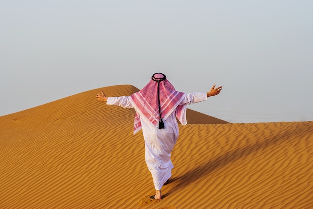 Portrait d'homme arabe assoiffé sur un milieu de désert jaune.