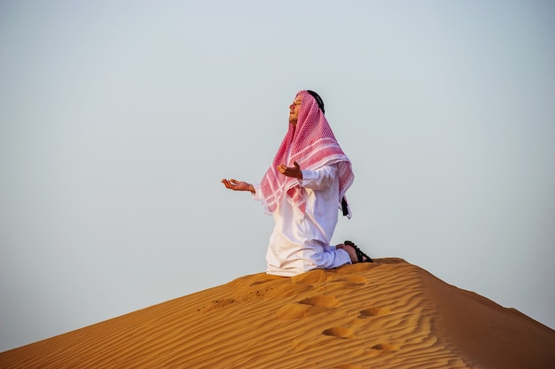 Portrait d'homme arabe assoiffé sur un milieu de désert jaune.