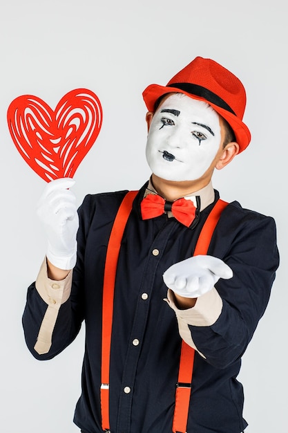 Portrait d'un homme artistclown MIME Montre un coeur isolé sur fond blanc en Studio