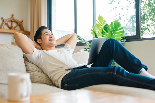 Portrait d'un homme asiatique assis sur un canapé à la maison