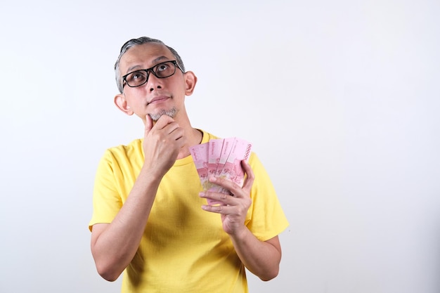 Portrait d'un homme asiatique avec une chemise décontractée qui a l'air heureux de tenir beaucoup d'argent dans la main