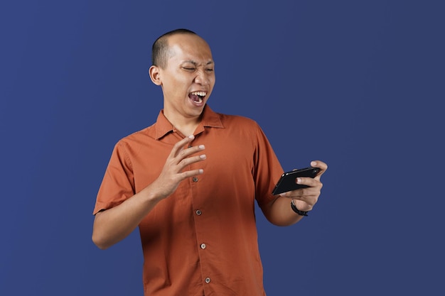 Portrait d'un homme asiatique choqué lisant des nouvelles choquantes et ayant l'air surpris. Concept de tournage en studio