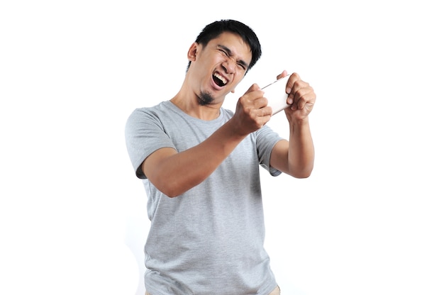 Portrait d'un homme asiatique en colère portant un t-shirt gris se fâcher sur le smartphone isolé sur fond blanc