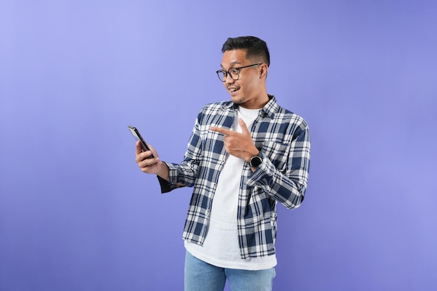 Portrait d'un homme asiatique joyeux tenant et montrant une carte de crédit et un téléphone portable avec un geste de la main