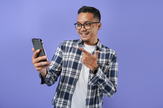 Portrait d'un homme asiatique joyeux tenant et montrant une carte de crédit et un téléphone portable avec un geste de la main