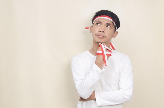 Portrait d'un homme asiatique pensant avec un ruban rouge et blanc sur la tête le concept d'indépendance