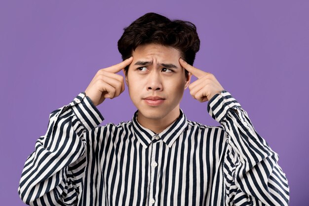 Portrait d'un homme asiatique pensif pensant et regardant ailleurs