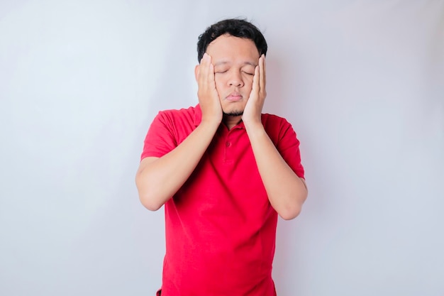 Un portrait d'un homme asiatique portant un t-shirt rouge isolé sur fond blanc a l'air déprimé
