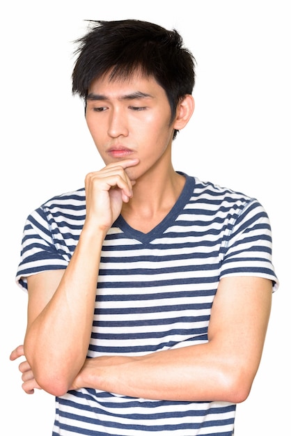 Portrait d'un homme asiatique sérieux pensant isolé contre le mur blanc