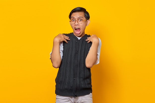 Portrait d'un homme asiatique surpris avec la bouche ouverte sur fond jaune