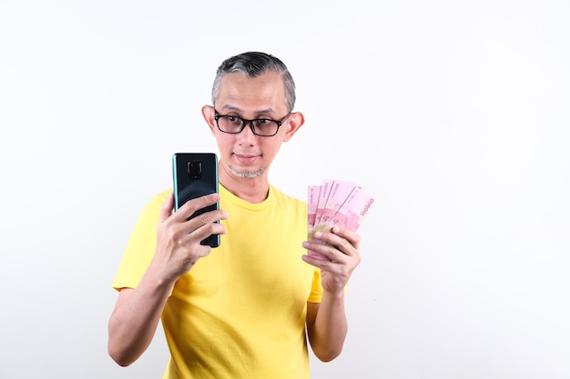 Portrait d'un homme asiatique avec un t-shirt décontracté qui a l'air heureux de tenir beaucoup d'argent dans la main